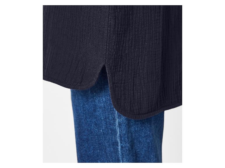 Close-up van een donkerblauwe blouse met afgeronde zoom en split, gedragen over jeans.