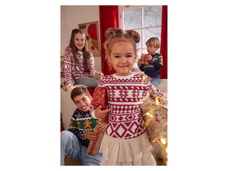 Vier kinderen in feestelijke kersttruien, met ingepakte cadeaus.