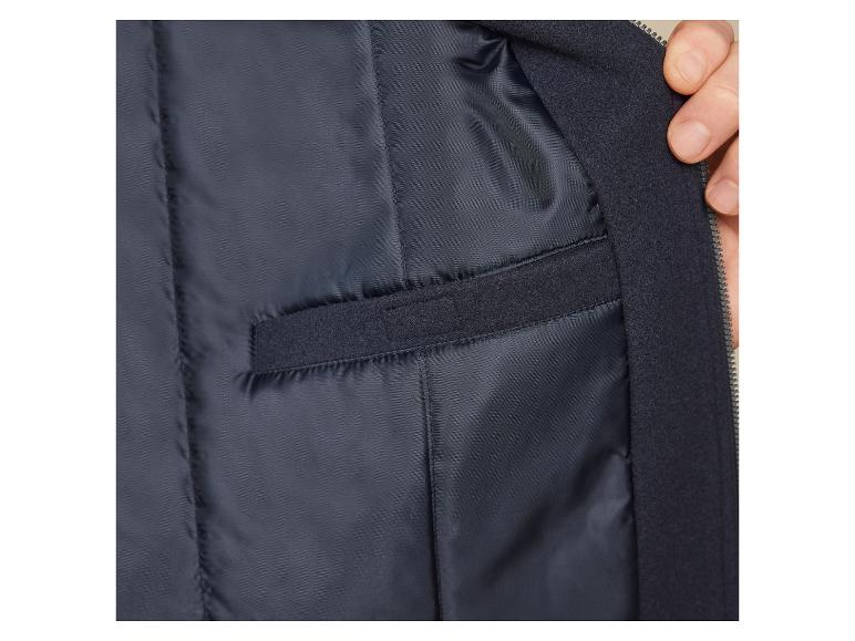 De binnenkant van een donkerblauwe jas met een rits en een zak.