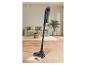Aspirateur balai sans fil avec lumières sur parquet avec liquide renversé dans le salon.