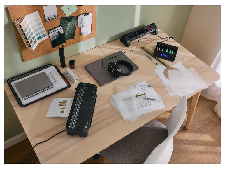 Bureau met TRONIC lamineerapparaat, stekkerdoos, batterijlader en kantoorbenodigdheden.