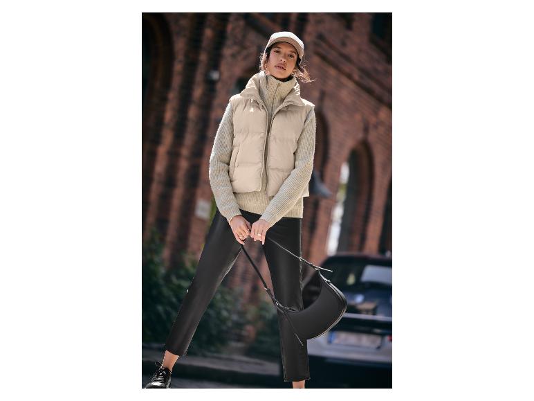 Femme en gilet beige, pull en maille et pantalon en cuir.