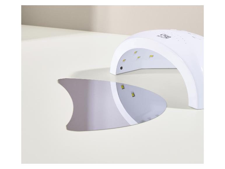 Lampe UV blanche pour ongles avec plaque inférieure amovible sur une surface claire.