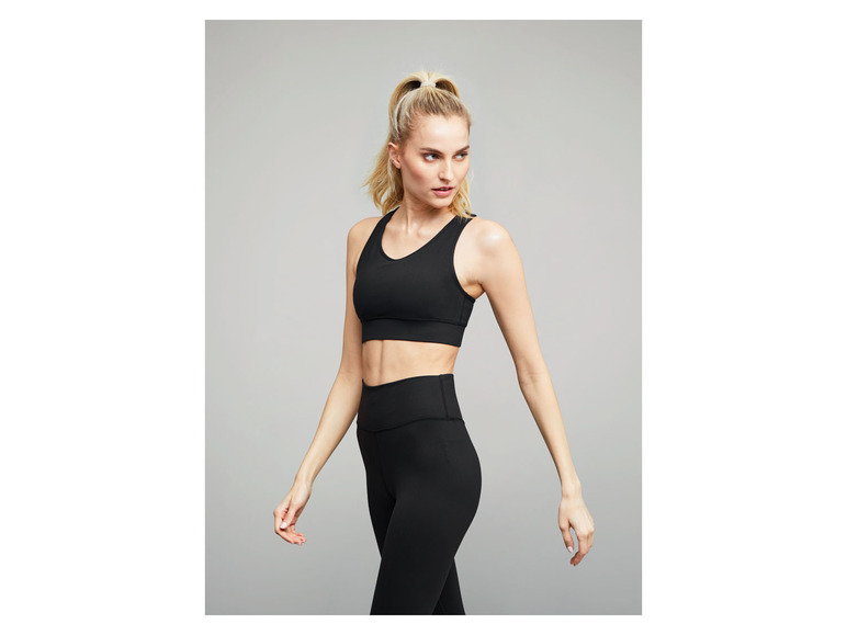 Een vrouw draagt een zwarte sportbeha en legging voor fitness.