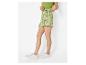 Vrouw in groene top en groen-wit gestreepte zebraprint minirok, witte sneakers.