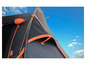 Een zwarte campingtent met oranje details tegen een blauwe lucht.