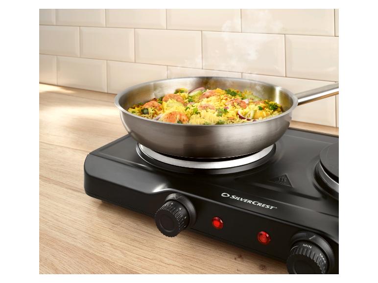 Poêle avec riz et crevettes sur une plaque de cuisson électrique portable noire.