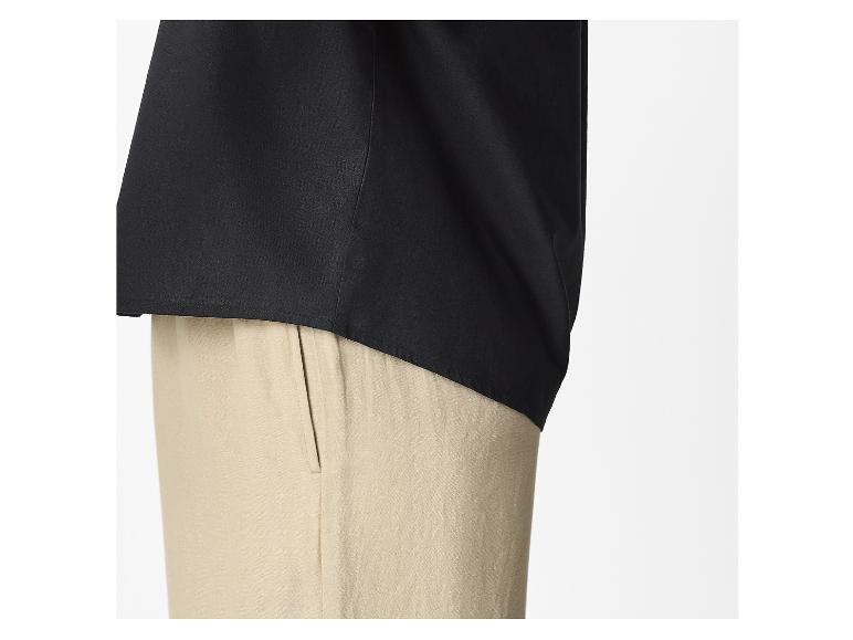 Onderkant van een zwart overhemd en beige broek