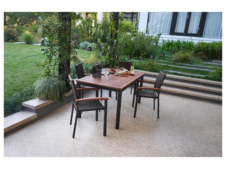Ensemble de salle à manger d'extérieur avec table en bois et chaises en osier dans le jardin.