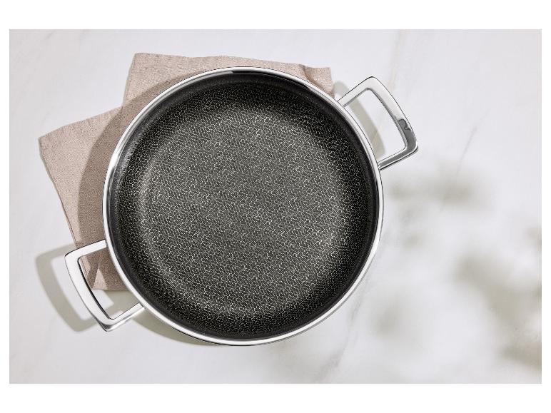 Koekenpan met metalen handvat op een theedoek op een wit marmeren oppervlak