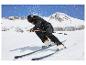 Homme en tenue de ski noire et casque dévalant une pente enneigée.