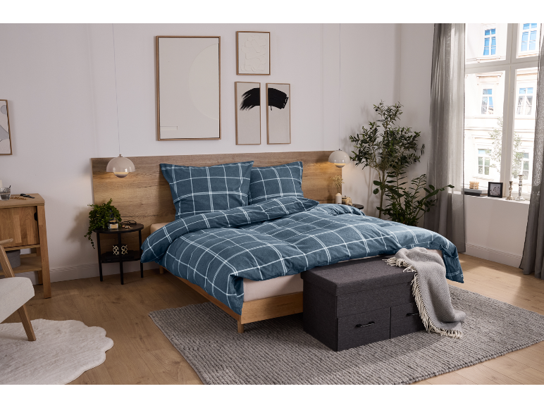 Chambre à coucher avec parure de lit à carreaux bleus, tête de lit en bois et tables de chevet.
