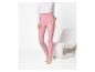 Femme en leggings roses et haut blanc à manches longues, debout à côté d'une chaise blanche.