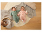 Deux bébés en grenouillères verte et rose sur un tapis.
