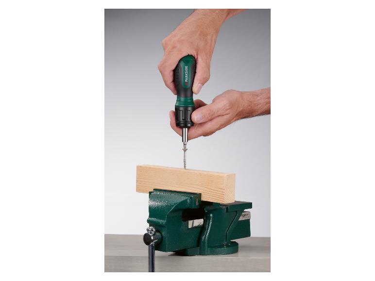 Une main utilise un tournevis Parkside pour visser une vis dans une planche de bois.