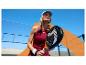 Vrouw met padelracket in sportkleding op zonnige buitenbaan.