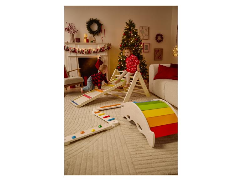 Twee kinderen spelen met houten speeltoestellen in een kerstversierde kamer.