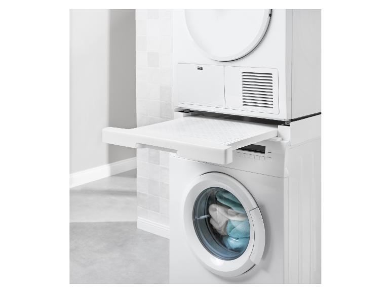 Gestapelde wasmachine en droger met uitschuifbaar plateau in een witte badkamer.