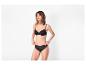 Femme en soutien-gorge et culotte en dentelle noire, posant sur fond blanc.