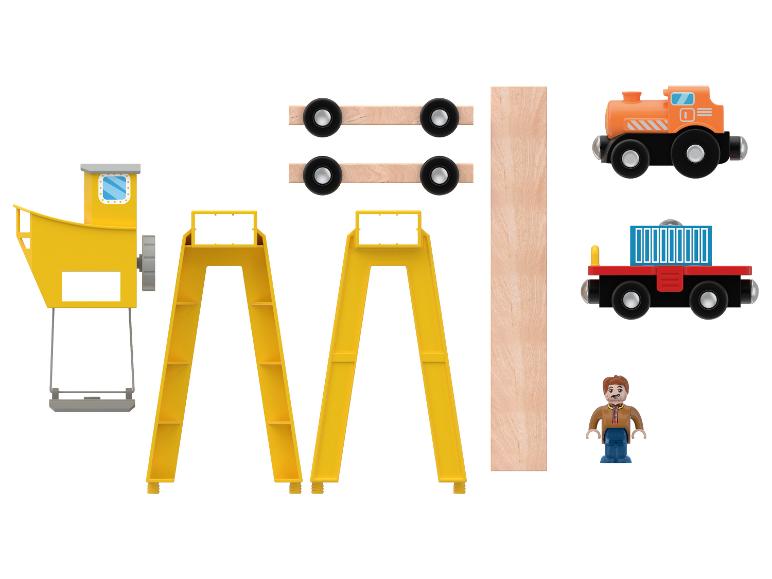 Jouets en bois, incluant une grue, des rails de train, des wagons et une figurine.