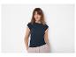 Femme en t-shirt côtelé bleu marine et pantalon beige, les mains dans les poches.