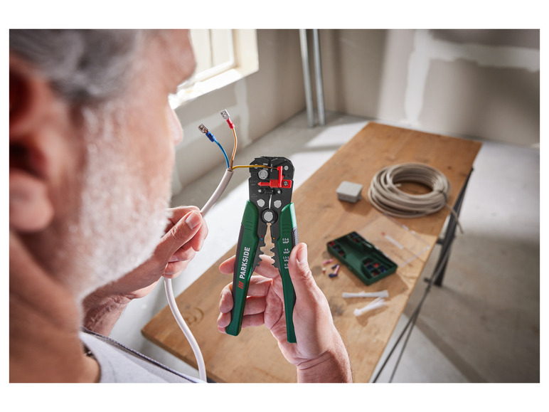 Een man gebruikt een Parkside kabelstripper om draden te strippen.