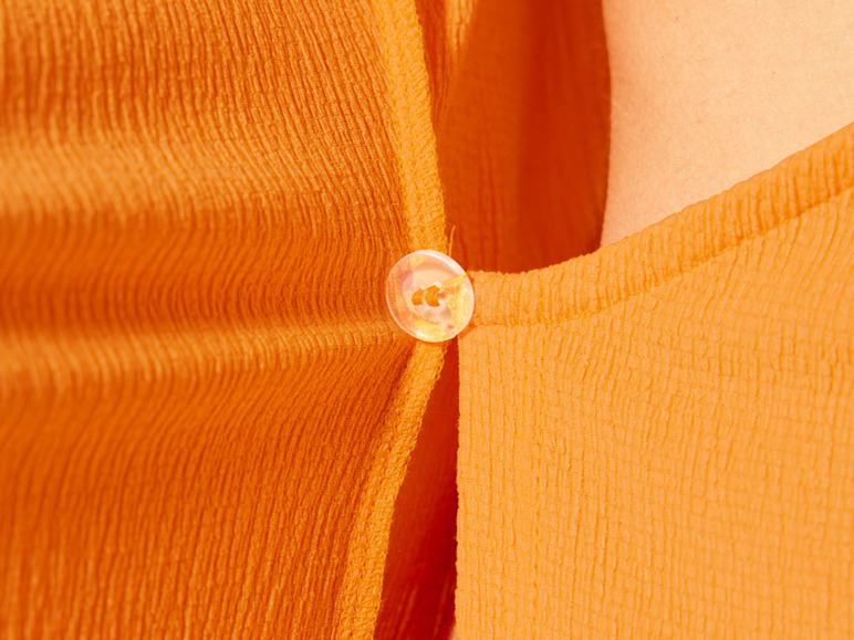 Gros plan sur une chemise orange avec un bouton.