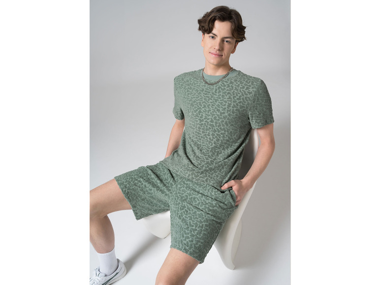 Man draagt een groene T-shirt en korte broek met luipaardprint.