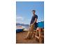 Man in blauw T-shirt en kaki broek op het strand met boten