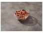 Amandes caramélisées dans un bol en verre avec une cuillère sur une surface grise.