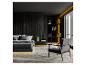 Moderne slaapkamer met zwart bed, donkere houten wand, boekenplank en fauteuil.
