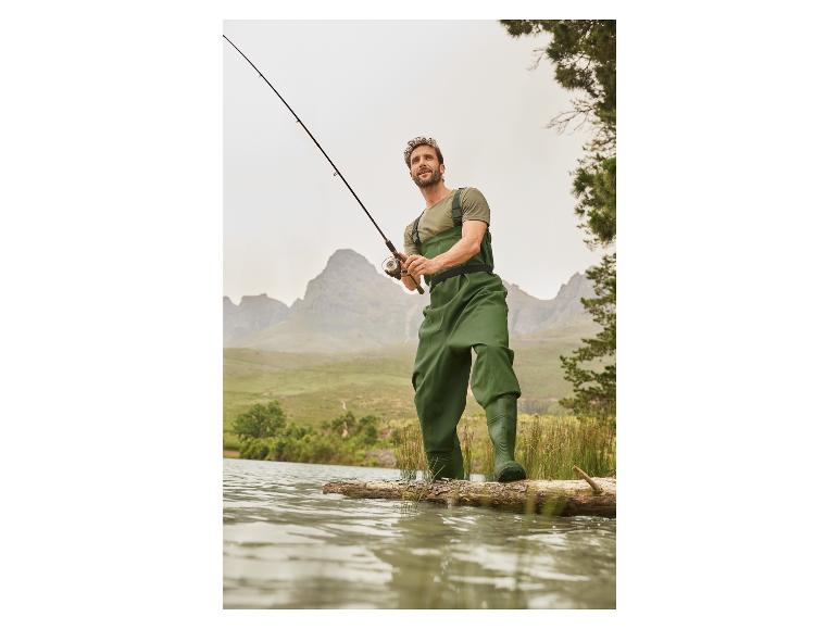 Visser in groene waders vist met een hengel.