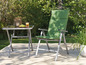 Une chaise de jardin verte avec une table en verre sur une terrasse.