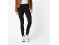 Femme en veste marron, t-shirt blanc, jean noir et baskets blanches.