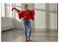 Lachende vrouw in rode trui, rood vest, jeans en sneakers met luipaardprint.