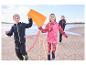 Kinderen in CRIVIT functionele broeken rennen op het strand met een vlieger