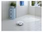 Robotstofzuiger reinigt een betegelde badkamer met een blauwe kast en een plant.
