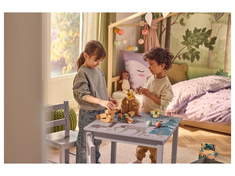 Twee kinderen spelen met bouwblokken en speelgoed aan een kindertafel met bosthema.