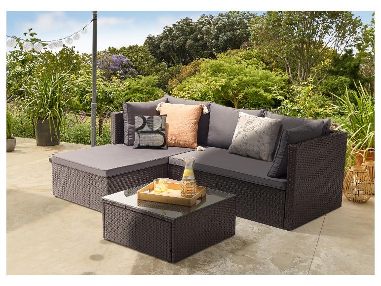 Grijze rotan loungeset met kussens, salontafel en decoraties.