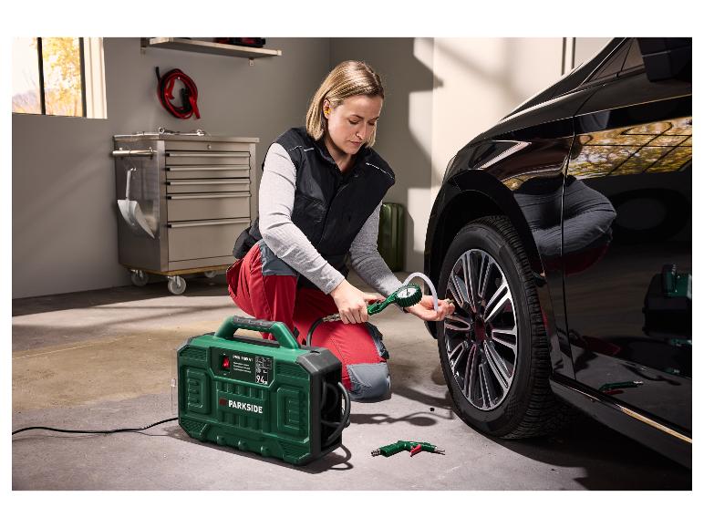 Vrouw pompt de band van een zwarte auto op met een draagbare Parkside compressor.