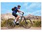 Cycliste sur un VTT électrique avec sac à dos et casque dans un paysage montagneux.