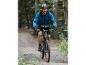 Een man op een mountainbike, met een blauwe jas, rijdt door het bos.
