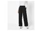 Zwarte pantalon met wijde pijpen en witte sneakers.