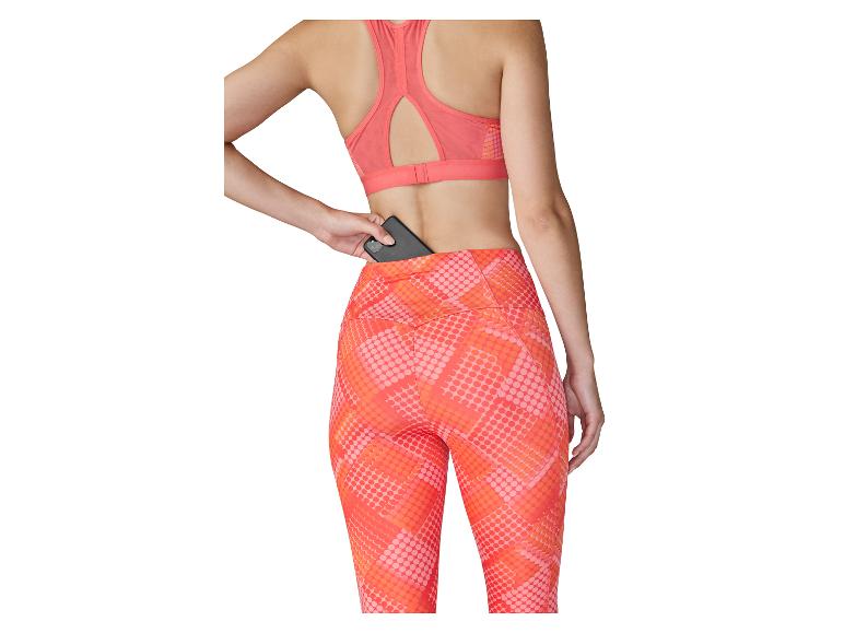Vrouw in sportbeha en legging met achterzak, waarin ze een telefoon bewaart.