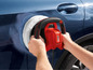 Un homme polit une voiture bleue avec une polisseuse rouge Ultimate Speed.