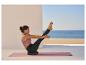 Femme faisant du yoga sur un tapis et un coussin d'équilibre au bord de la mer.