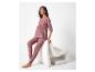 Femme enceinte en pyjama mauve, assise sur une chaise blanche.