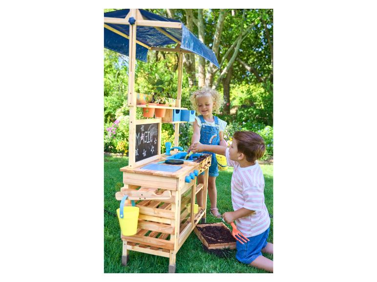 Twee kinderen spelen met een houten speelgoedkeuken en tuinset.
