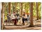 Een groep mensen geniet van een maaltijd aan een opklapbare tafel in het bos.
