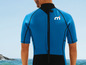 Een man draagt een blauw wetsuit met een M-logo op de rug.